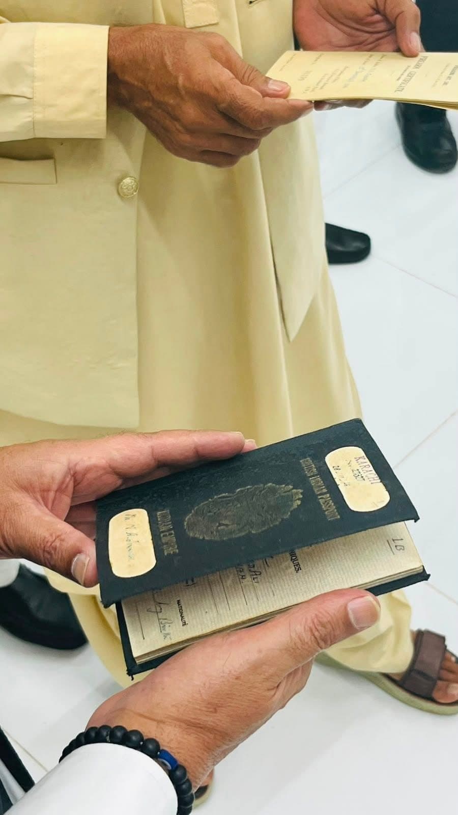 Hands holding an old black British Indian passport issued at Karachi