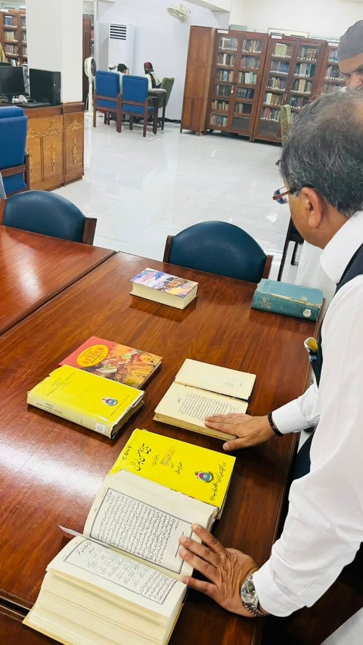 Urdu and English books open on a polished library table
