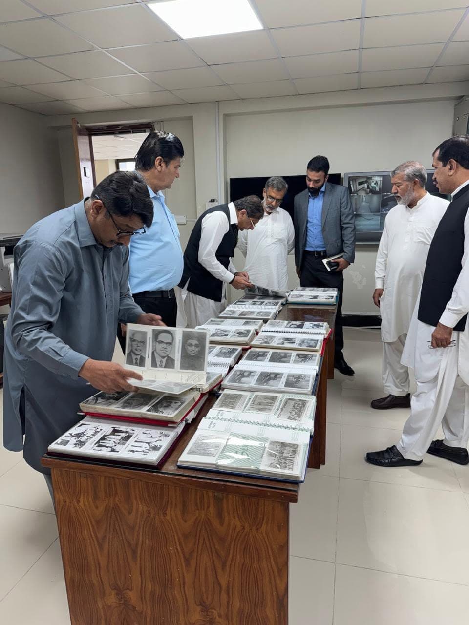 Visitors leaning over a long table covered with open photograph albums