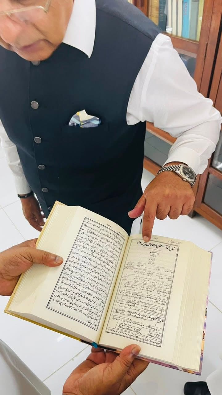 A finger pointing to a family tree printed in an Urdu book