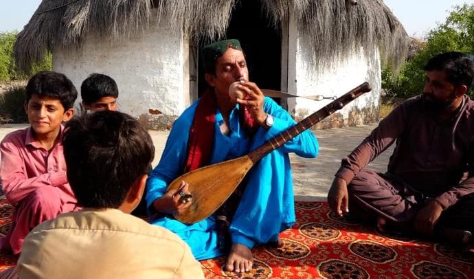 A musician playing the boreendo to children seated around him